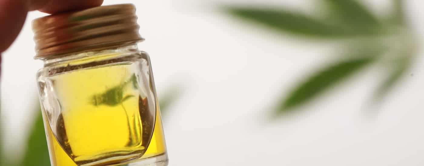 Cannabis oil is shown with a marijuana leaf in the background.