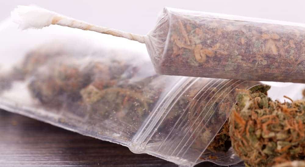 Marijuana is shown rolled in paper next to a bag.