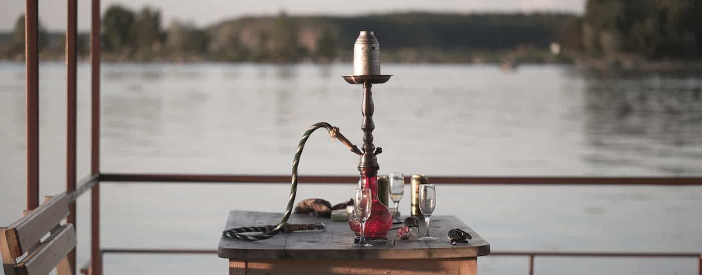 A hookah is shown on a table in front of a river.