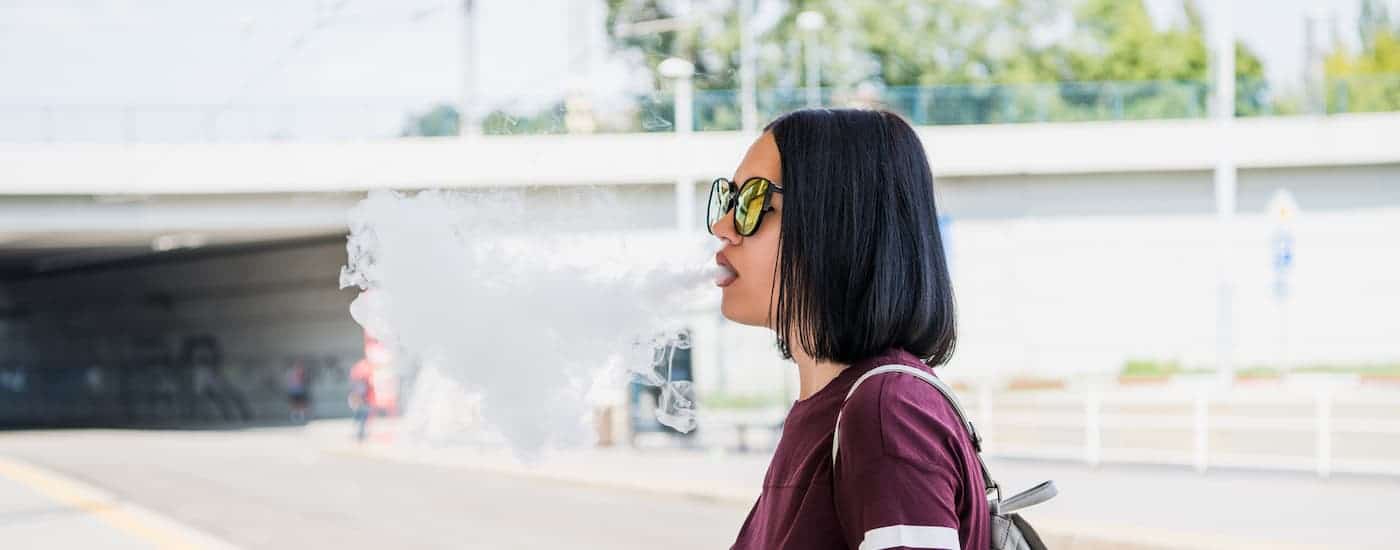 A girl is blowing vape smoke.