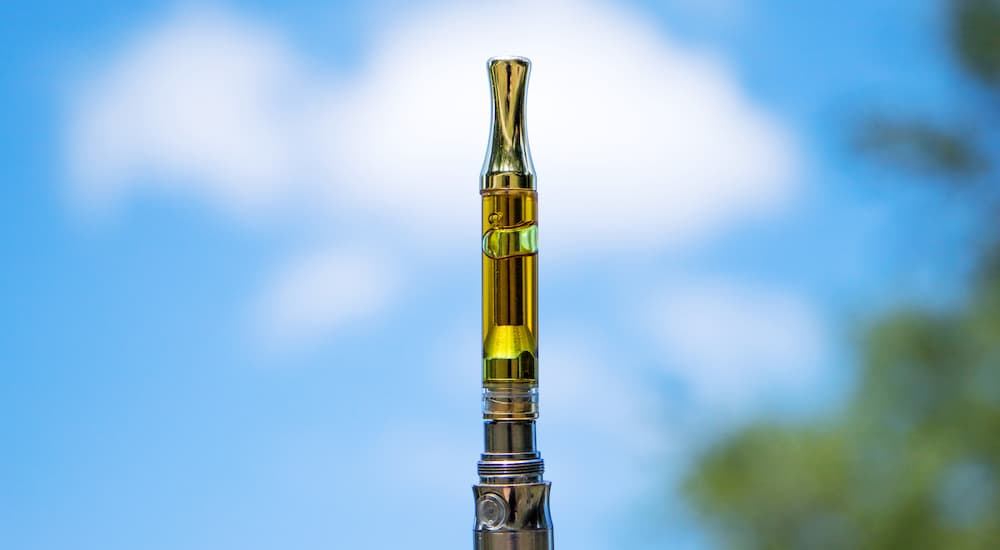 An oil vape is shown with a blue sky behind it.