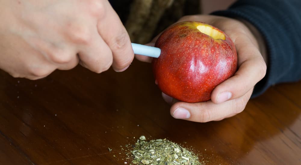 A man is using a pen to tunnel through an apple.