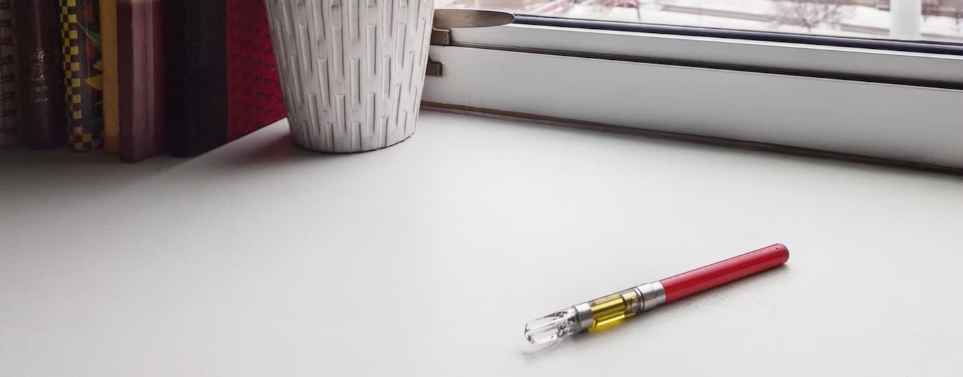 A vape pen with CO2 oil is on a windowsill. 