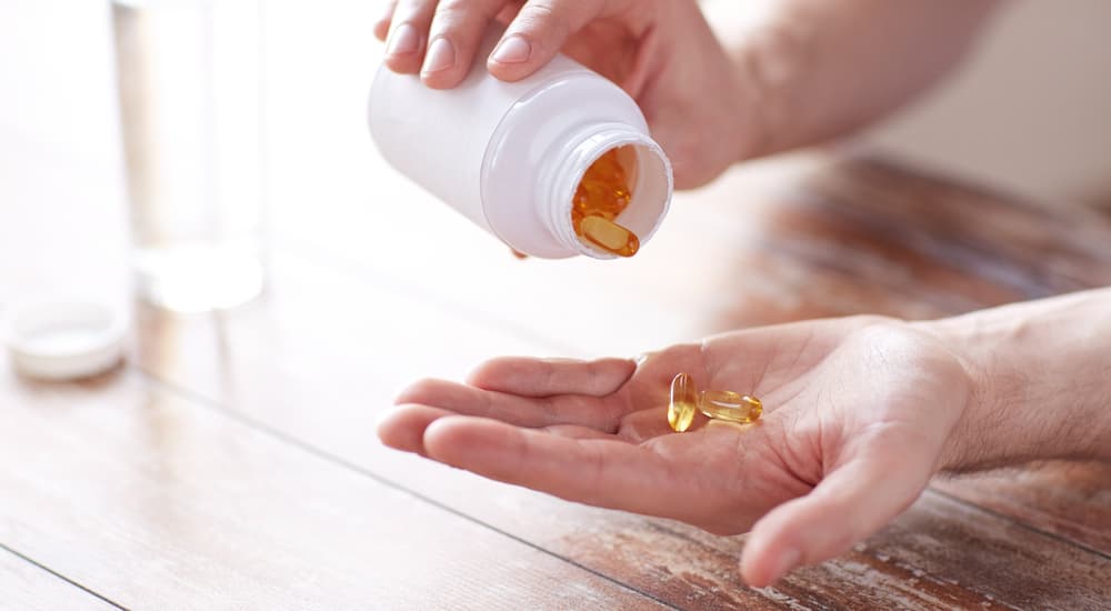 A bottle of capsules is being poured into a hand.